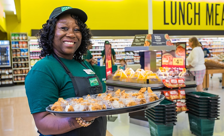 Harveys Supermarket associate smiling and holding a tray of food samples