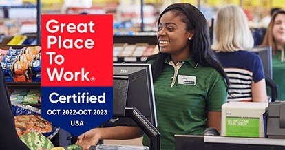 'Great Place to Work - Certified Oct 2022-Oct 2023' - Harveys Supermarket cashier smiling and checking out items