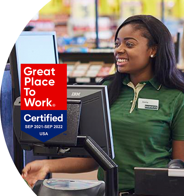 'Great Place to Work - Certified Sep 2021-Sep 2022' - Harveys Supermarket cashier smiling and checking out items