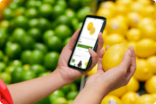 Person at grocery store in produce section with Harveys app holding a lemon