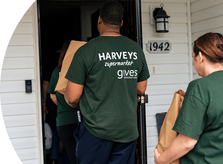 Harveys Supermarkets employee delivering a bag of groceries to a house