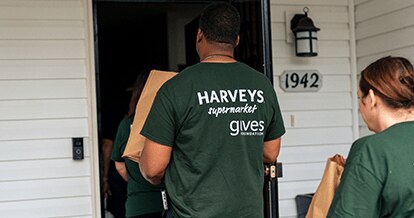 Harveys Supermarkets employee delivering a bag of groceries to a house