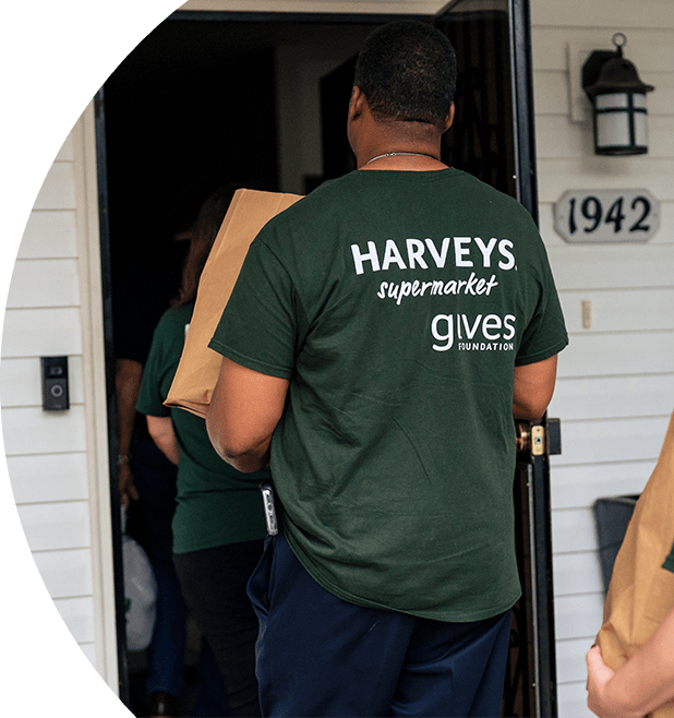 Harveys Supermarkets employee delivering a bag of groceries to a house