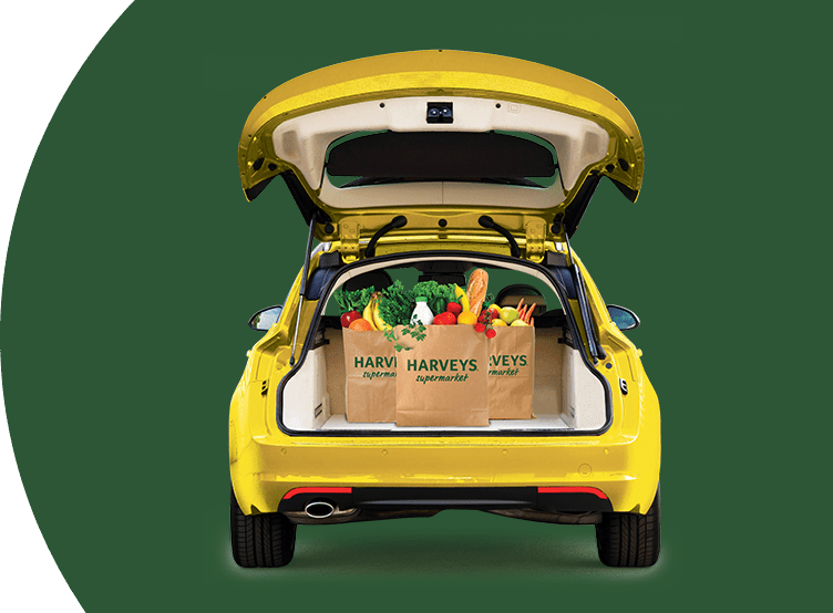 Bagged groceries inside the open trunk of a yellow car on a green background.