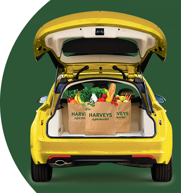 Bagged groceries inside the open trunk of a yellow car on a green background.