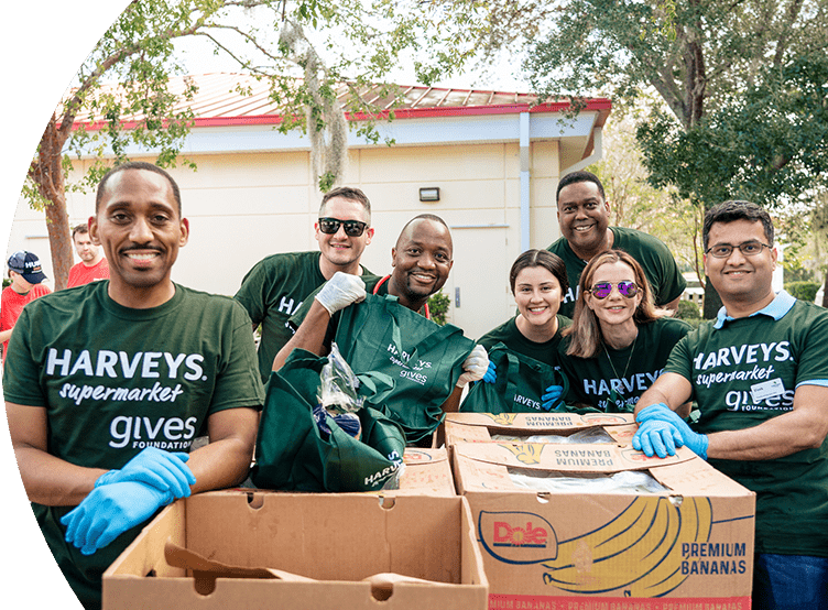 Group of smiling Harveys Supermarket employees wearing gives Foundation shirts.