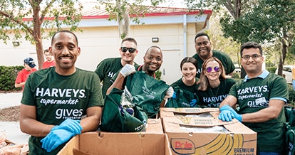 Group of smiling Harveys Supermarket employees wearing gives Foundation shirts.