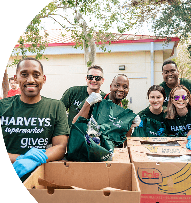 Group of smiling Harveys Supermarket employees wearing gives Foundation shirts.