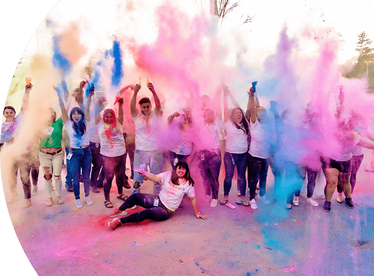 Group of people cheering and throwing colored powder in the air.