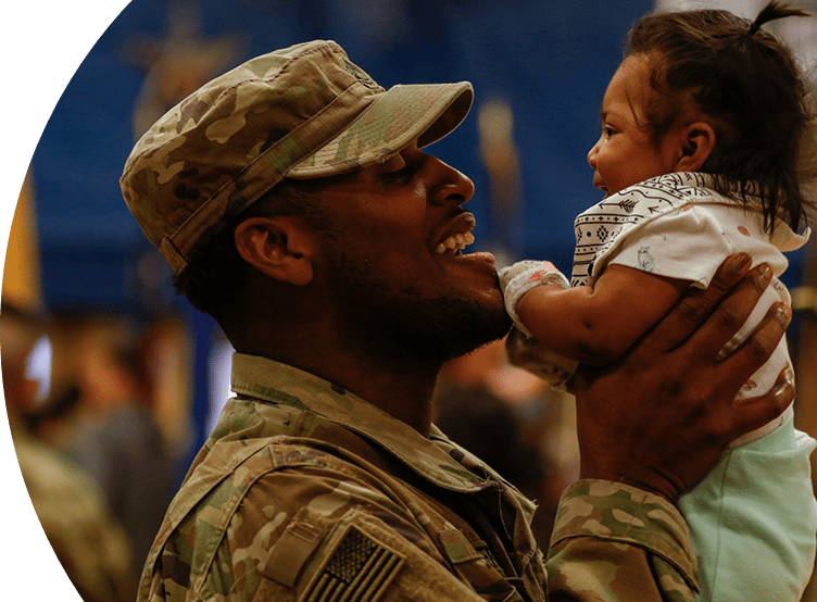 Smiling soldier in uniform picking up his baby.