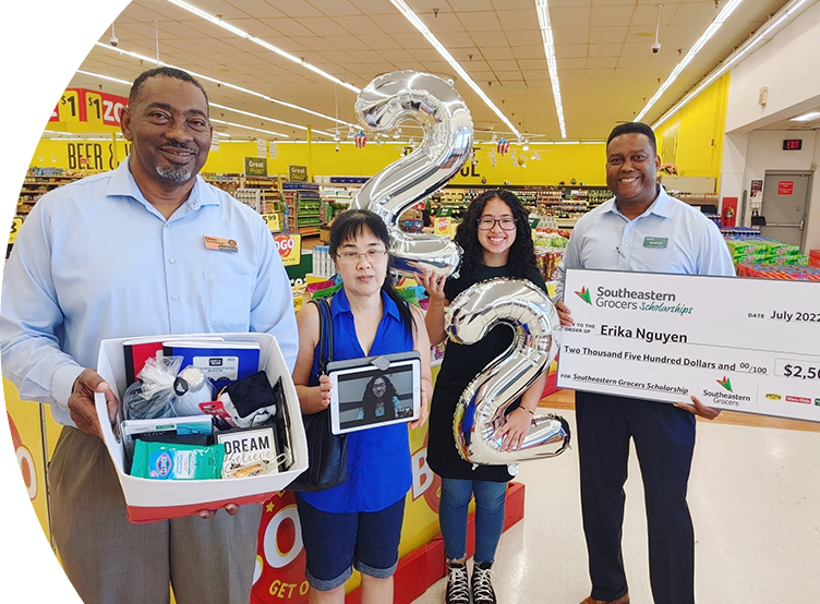 Four people smiling while one holds a big check.