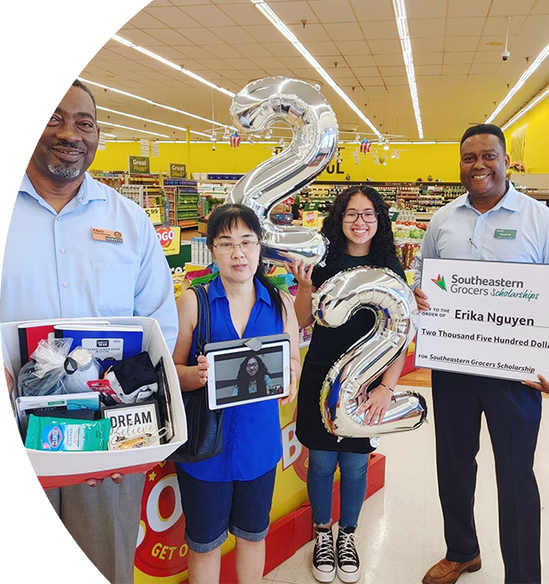 Four people smiling while one holds a big check.
