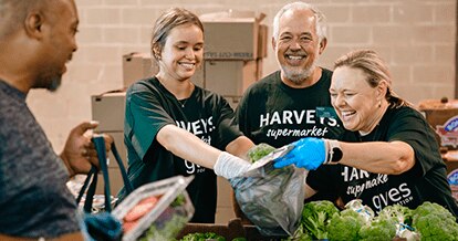 Gives Foundation volunteers joyfully arranging produce for donations.