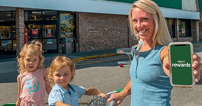 Woman and her 2 kids outside of a Harveys Supermarket holding her phone.