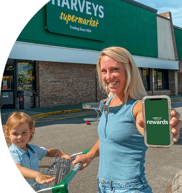 Woman and her 2 kids outside of a Harveys Supermarket holding her phone.