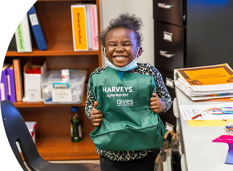 Girl happily holding a Haveys Supermaket gives foundation bag