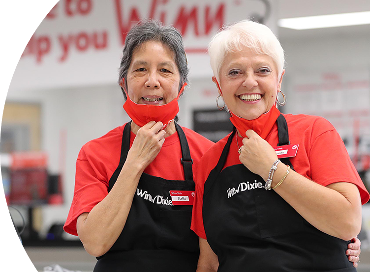 Two Winn-Dixie associates holding their masks down and smiling