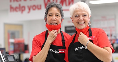 Two Winn-Dixie associates holding their masks down and smiling