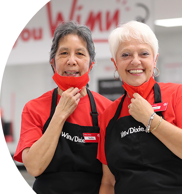 Two Winn-Dixie associates holding their masks down and smiling